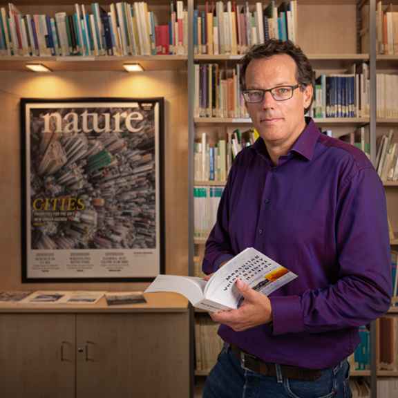 Professor Birkmann im IREUS Institut vor Bücherwand