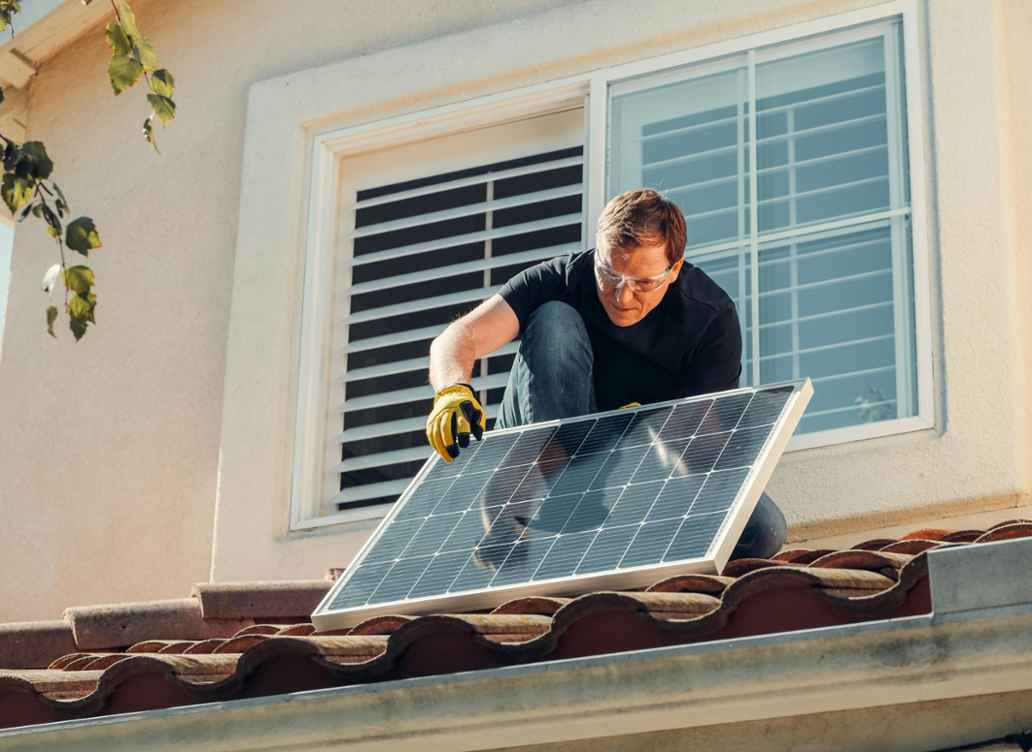 Mann installiert Solarpaneel auf dem Dach